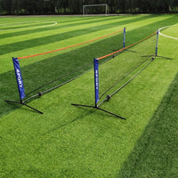 Two portable nets set up in a row on artificial turf, with a soccer goal visible in the background.