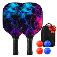 Two paddles with a blue and magenta network pattern and wrapped black grips, shown with a black carry case tied with a red ribbon, two orange balls and two blue balls.