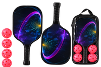 Two pickleball paddles printed with a magenta light arc over a deep blue face, shown with four pink balls and a carry case with a clear front panel holding a paddle and balls.